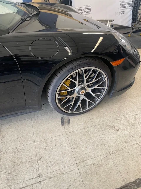 Front quarter panel and wheel of a black Porsche after repair